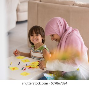 Arabic mother with little son in living room watering flowers - Shutterstock ID 609867824