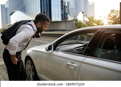 Arabic Muslim Businessman With Jacket On Shoulder Calling And Talking To Taxi Cab Driver For Lift From Work In The City