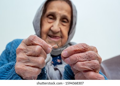 Arabic muslim old woman inserting thread in needle - Shutterstock ID 1594368307