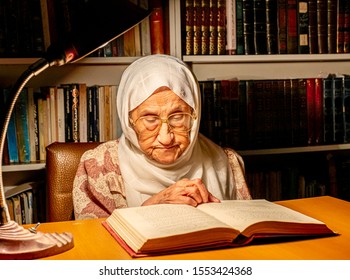 Arabic Muslim Old Woman Reading Books At Night With Table Lamp Light