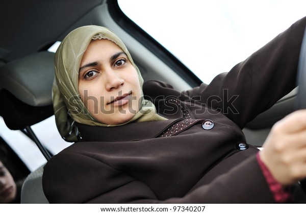 Arabic\
Muslim woman driving car wearing traditional\
scarf