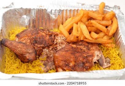 
Arabic Syrian Cuisine Of Grilled Barbecued Chicken With Yellow Basmati Rice And French Fries, Fried Potatoes Fingers Served In A Foil Plate In A Close Up View, Selective Focus