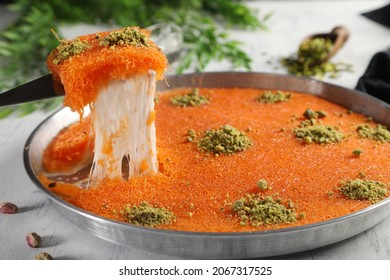 Arabic traditional kunafa. desserts rough konafa in tray sweet with pistachio and pine on top. close up