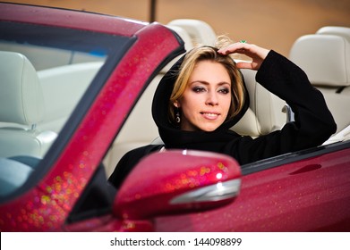 Arabic Way Dressed Yang Woman Posing In Red Car In Desert.