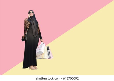Arabic woman holding a shopping bag on pink and yellow background, Shopping concept