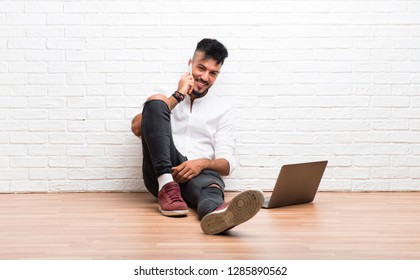 Arabic young man using mobile phone sitting on the floor
