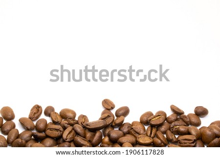 Arabica coffee beans are located on a white background with the main focus on the bottom of the photo, in which coffee is harmoniously sprinkled