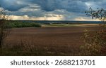 Arable field under a dramatic sky with rays of sunshine through the clouds at autumn
