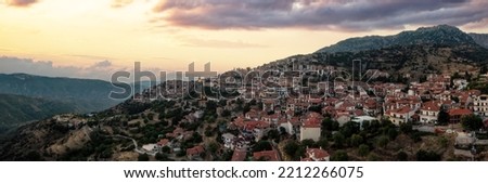 Arachova Greece mountain town aerial panoramic view. Traditional houses and stone tower clock cloudy sky at sunset