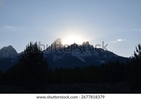araffe mountain range with sun shining behind it and trees
