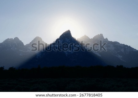 araffes in the foreground of a mountain range with a sun shining through the clouds