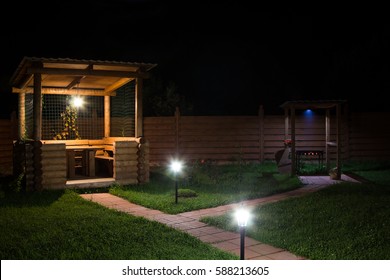 Arbor And Barbecue In The Backyard At Night