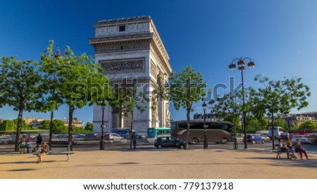 The Arc de Triomphe (Triumphal Arch of the Star) is one of the most famous monuments in Paris, standing at the western end of the Champs-Elyseees. Traffic on circle road. Blue
