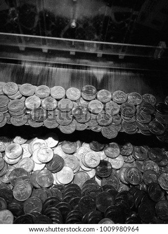 Arcade coin pushing gambling game with silver quarters - Black and White grainy instagram style filtered image