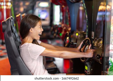 Arcade game machine adult woman having fun playing racing car videogame driving virtual sports cars.