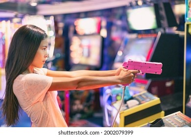 Arcade game machine adult woman shooting gun video games playing light shoot videogame virtual reality.