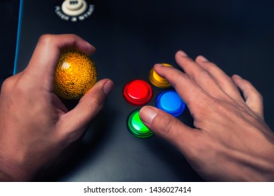 Arcade gamer holding a yellow bubble top joystick and playing on a four button layout arcade machine.