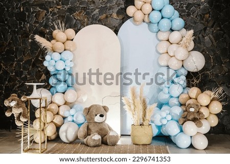 Arch with bears on background balloons. Photo-wall decoration space or place with beige, brown, blue balloons. Celebration baptism concept. Birthday party for boy. Trendy autumn decor with dry leaves.