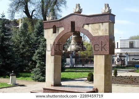 Arch with a bronze bell at the cemetery of the memorial complex 