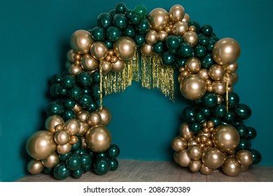 Arch of dark green and gold balloons on a green background