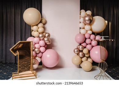 Arch decorated with pink, brown, and gold balloons. Copy space. Birthday arch for 1 year and a background photo wall. Reception at a birthday party.