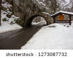 Arch and road in mountains in winter forest, Miskolc, Hungary. Miskolc road sign and medieval arch in mountain. Road in winter snowfall. Snowy highway. Road architecture. Traffic through mountain.