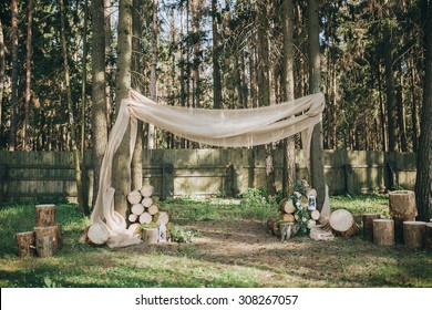 Arch For The Wedding Ceremony Of Burlap And Wooden Logs In Pine Forest