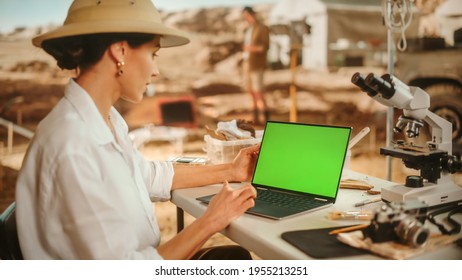 Archaeological Digging Site: Female Archaeologist Using Green Screen Chroma Key Display Laptop, Analysing Fossil Remains, Ancient Civilization Culture Artifacts. Historians work on Excavation Site