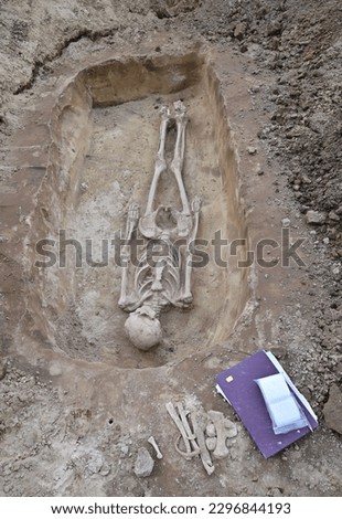 Archaeological excavation of a human skeleton.Archaeologists use meticulous work to uncover the graves of people who lived thousands of years ago.Finds and notebook can be seen next to the excavation.