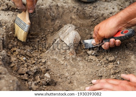 Archaeological excavations, archaeologists work, dig up an ancient clay artifact with special tools in soil