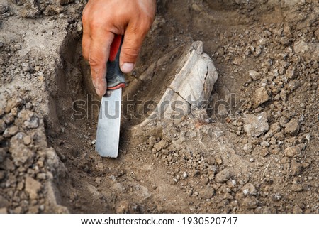 Archaeological excavations, archaeologists work, dig up an ancient clay artifact with special tools in soil
