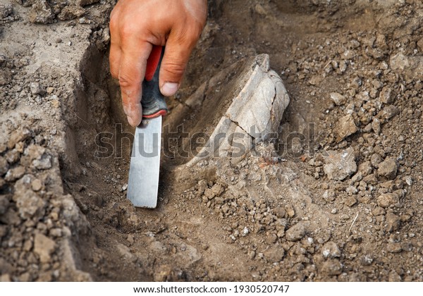 Archaeological excavations,\
archaeologists work, dig up an ancient clay artifact with special\
tools in soil