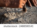 An archaeologist cleans a found artifact in the form of bones with a brush. Historical reconstruction of archaeological research of the 19th century. Close-up on the artifact.