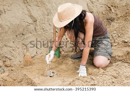 Archaeologist working in field, carefully revealing ancient skull