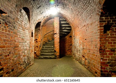 Arched corridor of the old Prussian fortress of red brick, ending with a spiral staircase - Powered by Shutterstock