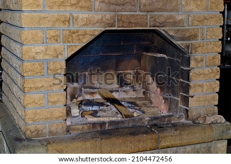 Arched fireplace with a smoldering fire. Ashes fly over fire. View of a traditional stone fireplace with wood. Firewood in the fireplace to light the fire.