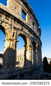 Arched vaults and rectangular openings in walls of ancient Roman amphitheater, traces of time and past centuries are visible on walls...