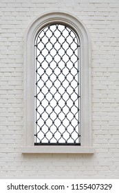 arched window with wrought iron lattice and decorative figures in the brick wall. window isolated with clipping path