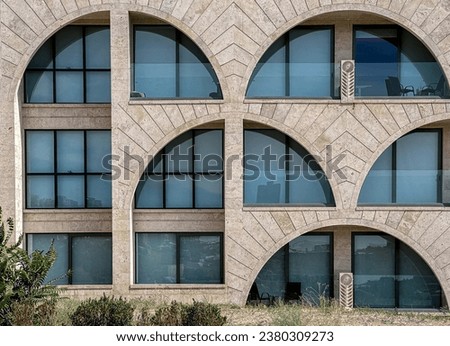 Arched windows on stone wall of modern city building. Architecture exterior in detail