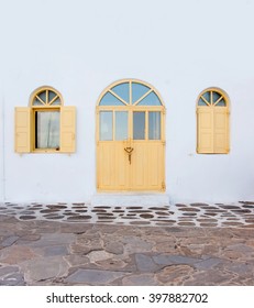 Arched wooden yellow door and windows on the whitewashed building.