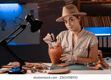 Archeologist working late night in office with brush and old vase. Copy space - Powered by Shutterstock