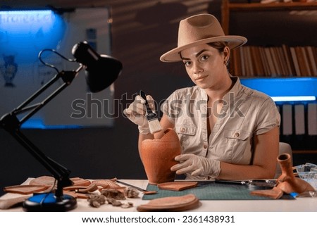 Archeologist working late night in office with brush and old vase. Copy space 商業照片 © 