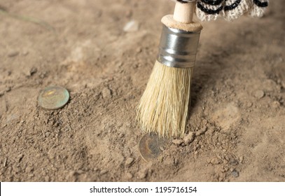 
Archeology Female Hand Holds Brush A Tassel Excavation Of Rare Materials Treasure Hunt And Archeology Find Rare 
Gold Coins In Sand 
