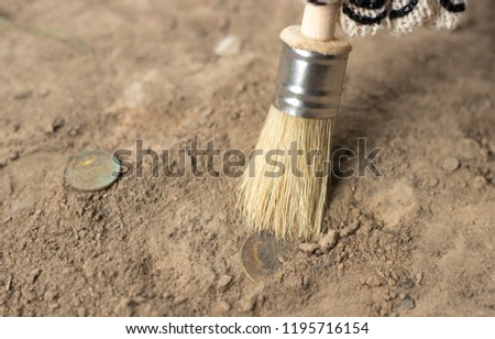 
archeology female hand holds brush a tassel excavation of rare materials treasure hunt and archeology find rare 
Gold coins in sand 