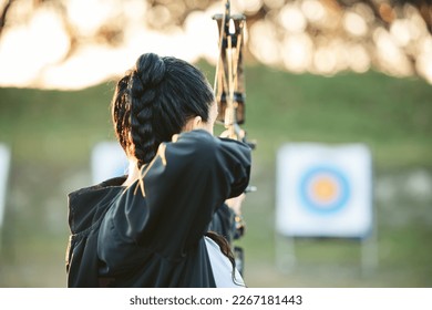 Archer, arrow target training and practice for archery competition, athlete challenge or competitive shooting. Sports field girl, bow hunting and woman focus on precision, aim or back view objective