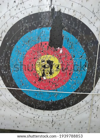 Archery target close up with many arrow holes in Gold, red, blue and black 