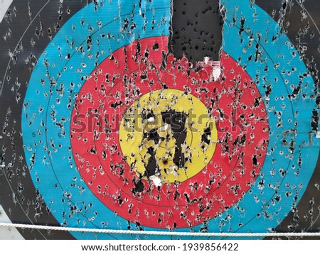 Archery target close up with many arrow holes in Gold, red, blue and black 
