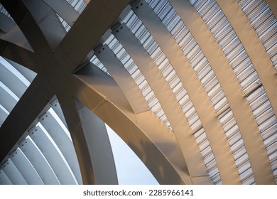 Arches of an abstract metal construction with the sun hitting the golden hour.