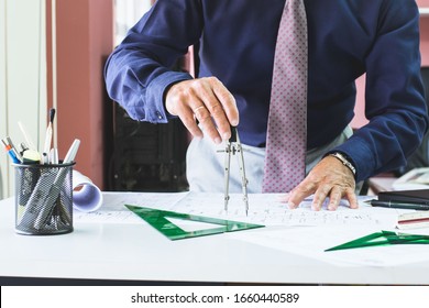 Architect With Blue Shirt And Tie With A Compas In His Hand Tracing On A Plane