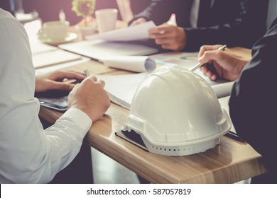 Architect And Businessman Planning Meeting To Work With Commitment, Set Mind.Focus White Safety Helmets Is Foreground.